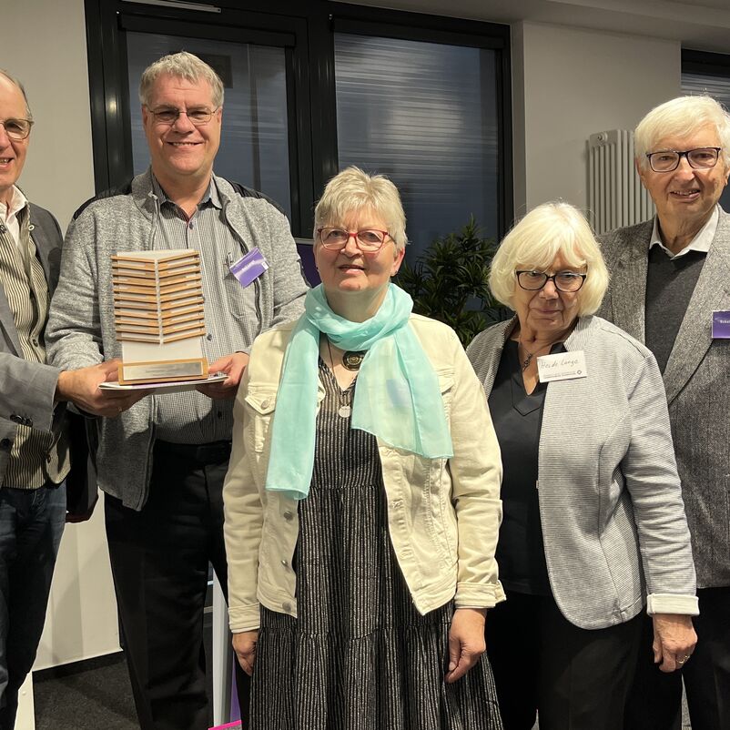 Eine Gruppe von Menschen steht mit ihrem Preis in Händen vor der Kamera. 