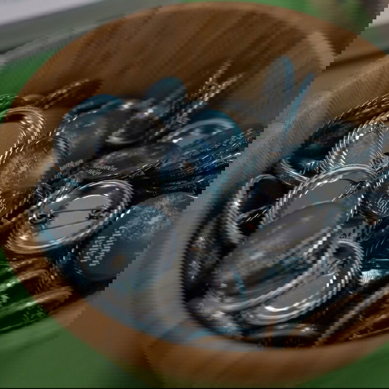 In einer Holzschüssel liegen Anstecker mit der Aufschrift "Glauben teilen".