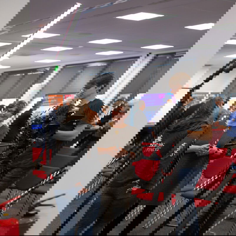 Drei Personen unterhalten sich. Es ist Kamera- und Lichttechnik aufgebaut.