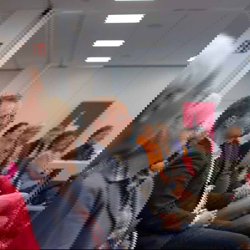 Eine vollbesetzte Stuhlreihe des Publikums.