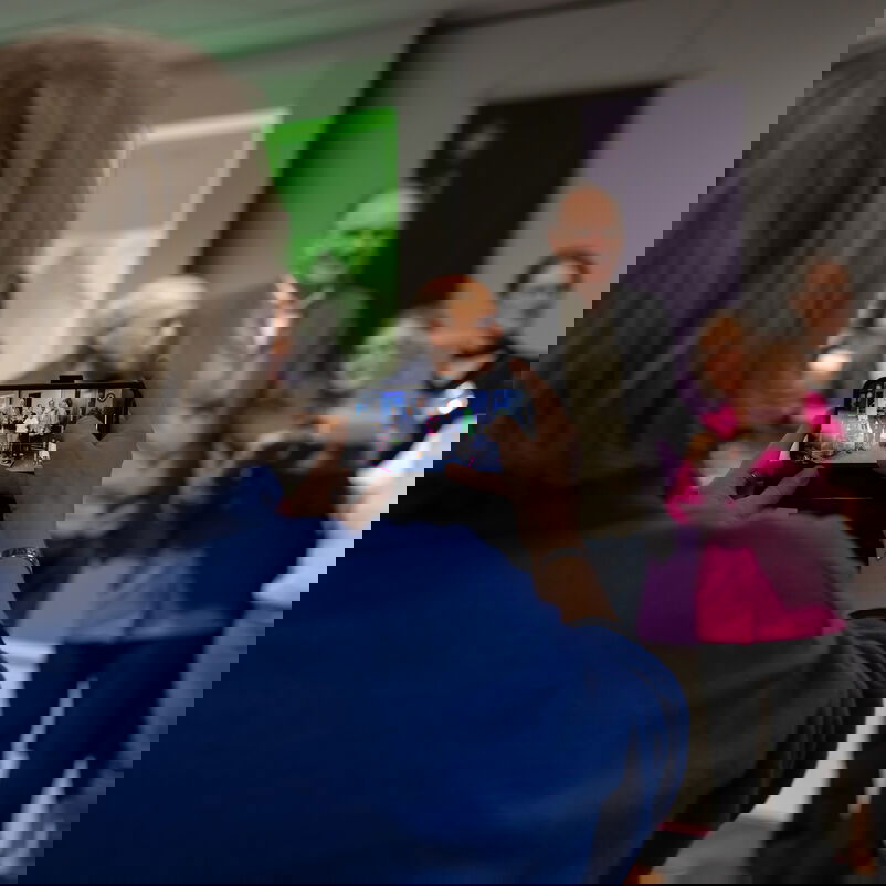 Eine weiblich zu lesende Person fotografiert mit dem Handy eine Preisträgergruppe auf der Bühne.