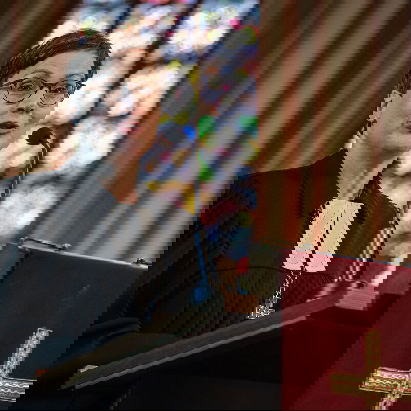 Eine weiblich zu lesende Person im Talar steht an einem Redepult.