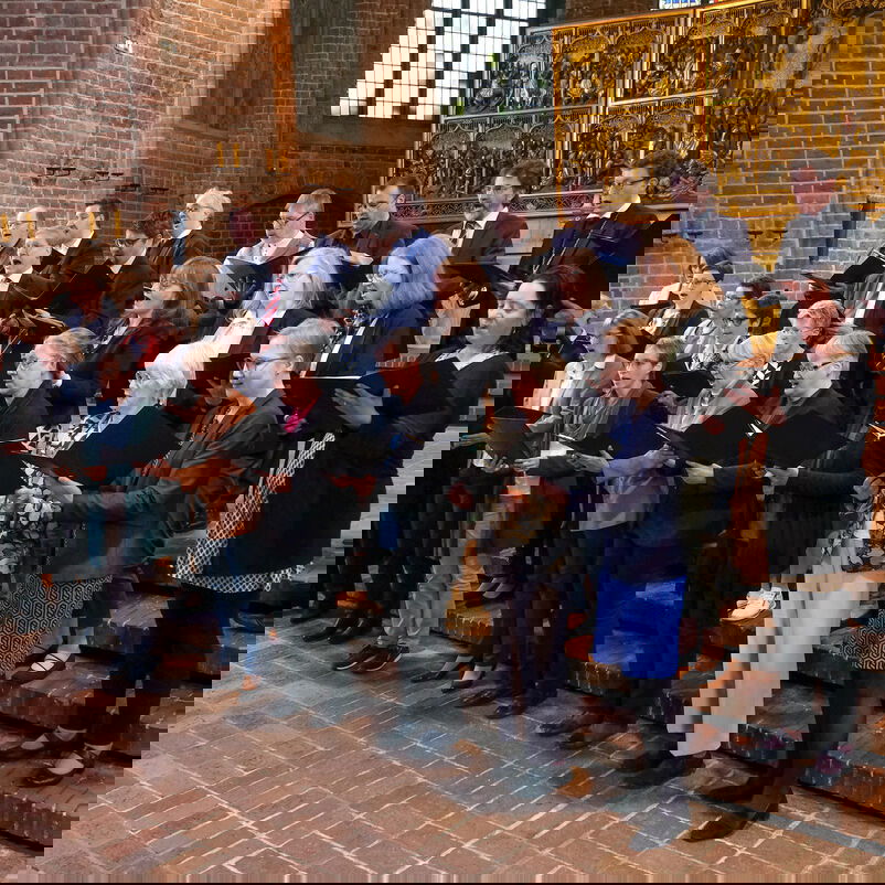 Weiblich und männlich zu lesende Personen stehen als Chor zusammen.