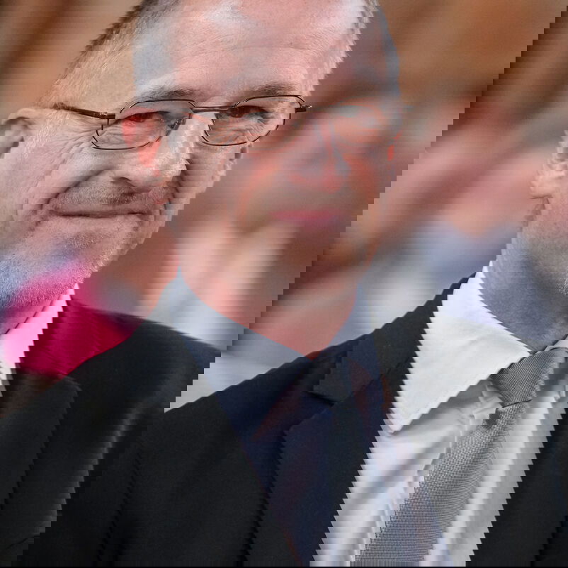 Eine männlich zu lesende Person lächelt.