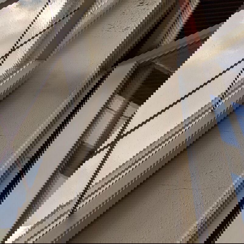 Zu sehen ist der Raum zwischen zwei Fensterscheiben, in dem der Putz bröckelt.