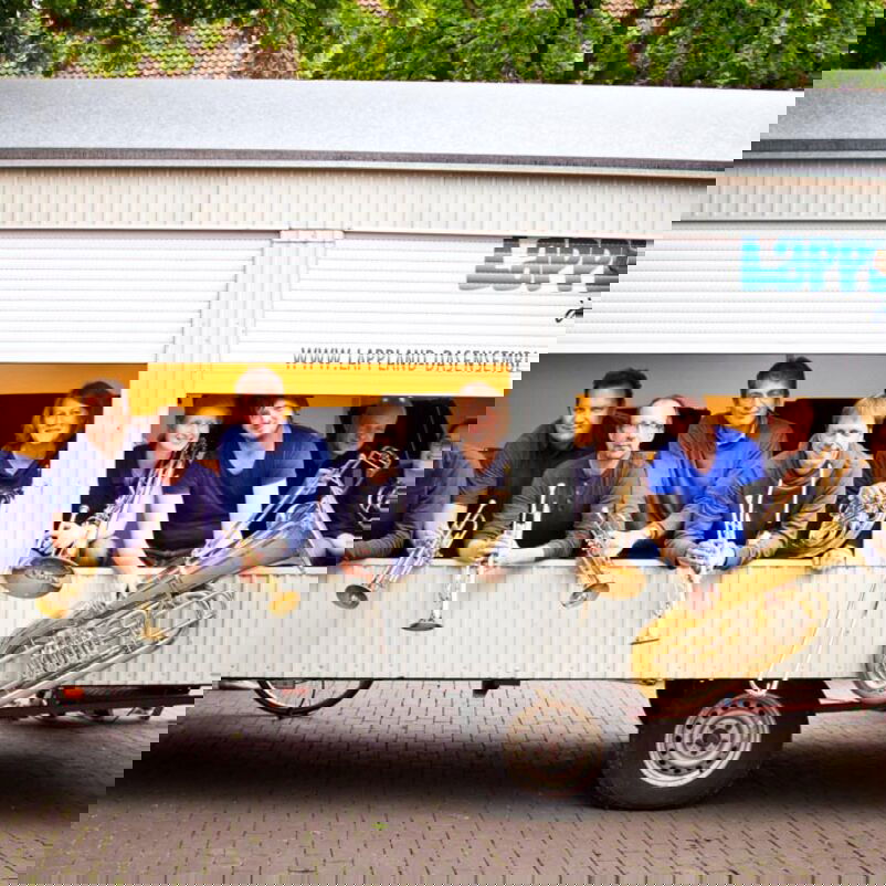 eine blaesercombo sitzt in einem geoeffneten bauwagen mit instrumenten in der hand