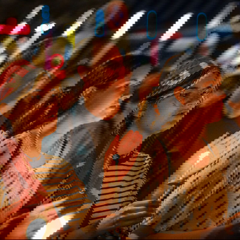 Weiblich und männlich zu lesende Personen halten Kerzen in den Händen.