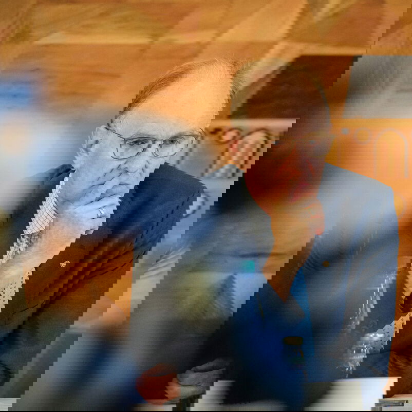 Eine männlich gelesene Person sitzt am Tisch.