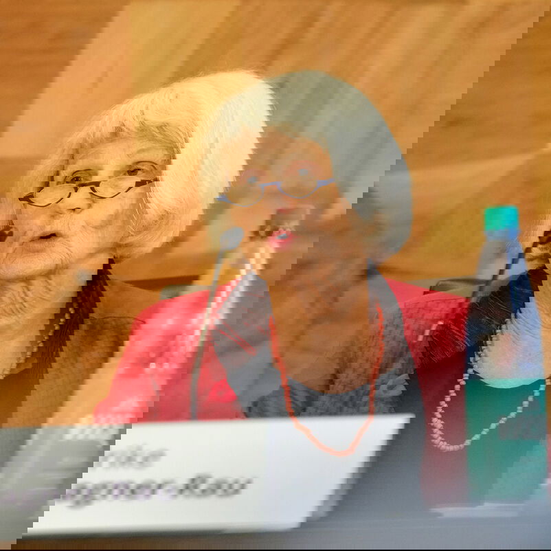 Eine weiblich gelesene Person spricht an einem Mikrophon.