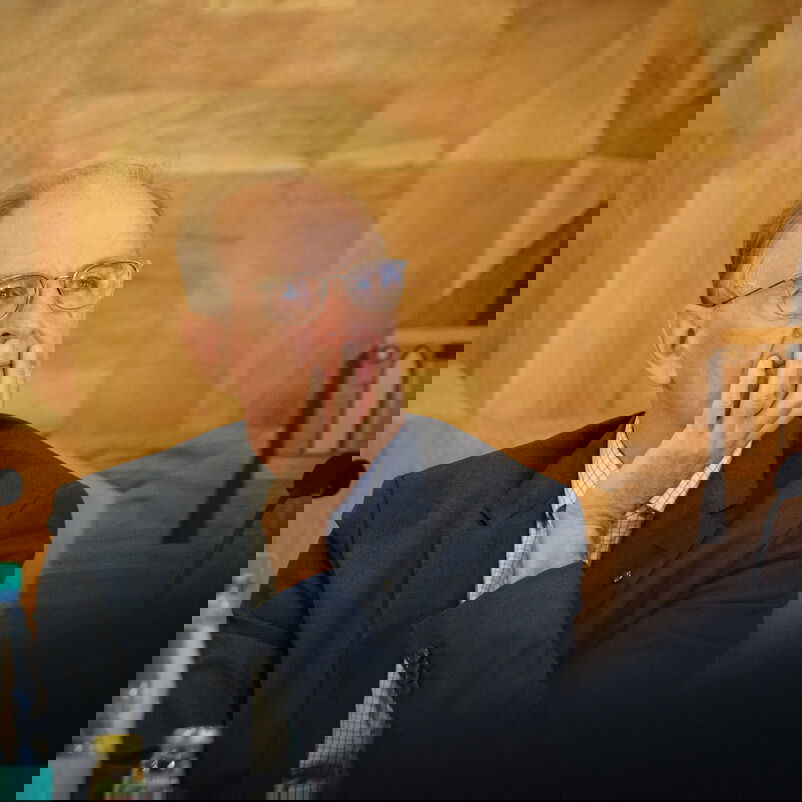 Eine männlich gelesene Person stützt sein Kinn in seine Hand.