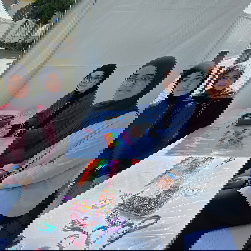 Frauen mit Kopftuch machen Perlenarmbänder.