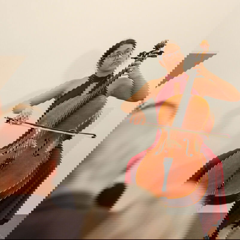 Eine weiblich zu lesende Person spielt auf einem Cello.