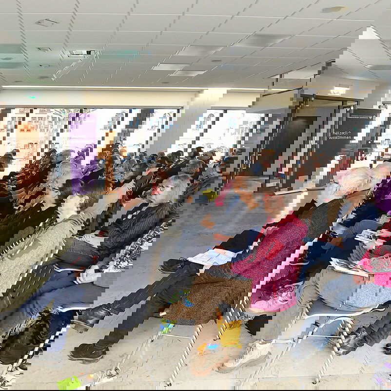 Menschen sitze in Reihen und hören einen Vortrag.