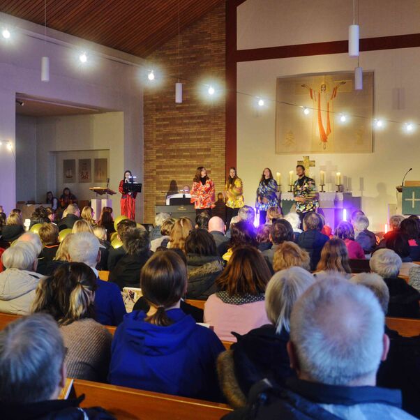 Ein Gottesdienst mit vielen Menschen. Ganz vorne stehen Jugendliche in Abba-Kostümen.