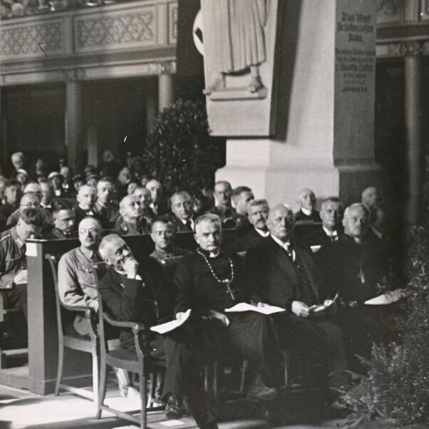 Das Schwarzweiß-Bild zeigt einen Kircheninnenraum mit vollbesetzten Kirchenbänken.