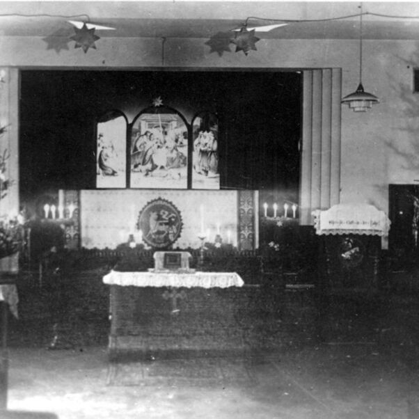 Das Schwarzweiß-Bild zeigt eine notdürftig eingerichtete Kirche mit Weihnachtsbäumen.