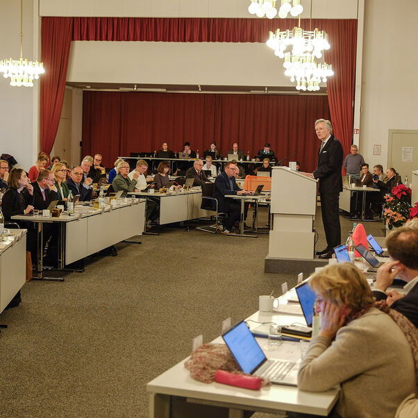 Mehrere Person sitzen an Tischen in einem Saal