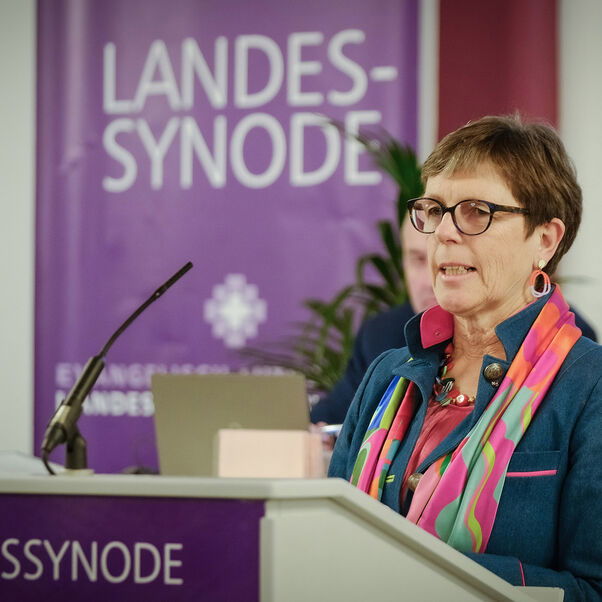 Eine weiblich gelesene Person mit kurzen, braunen Haaren am Redepult. 