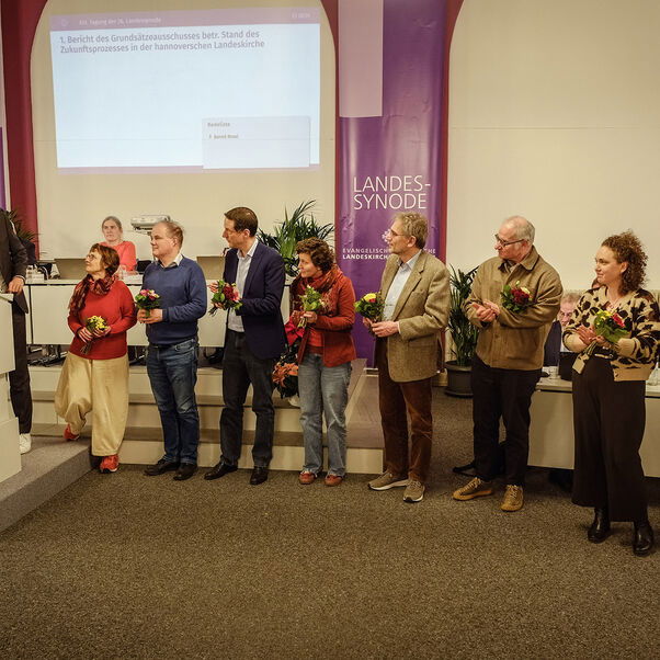 Eine Gruppe von Personen stehen mit jeweils einem Blumenstrauß in der Hand in einer Reihe nebeneinander.