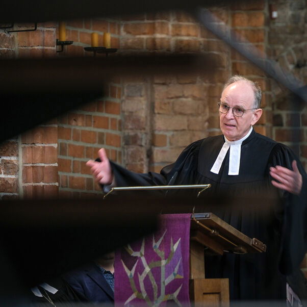 Eine männlich lesbare Person an einer Kanzel in einer Kirche