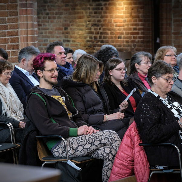 Mehrere Personen in Kirchenbänken