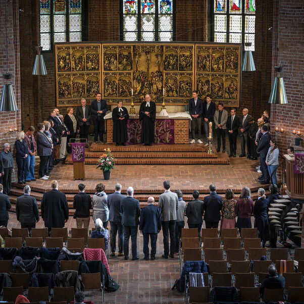 Viele Personen stehen rund um den Altar in einer Kirche