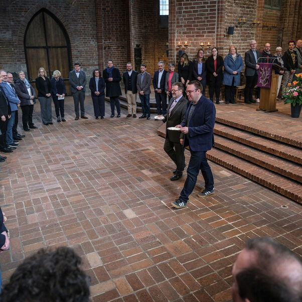 Viele Personen stehen im Halbkreis in einer Kirche