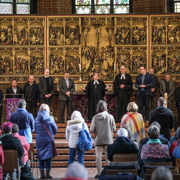 Viele Personen stehen vor dem Altar in einer Kirche