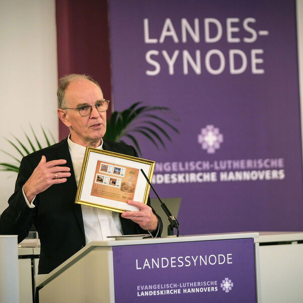 Eine männlich lesbare Person an einem Rednerpult