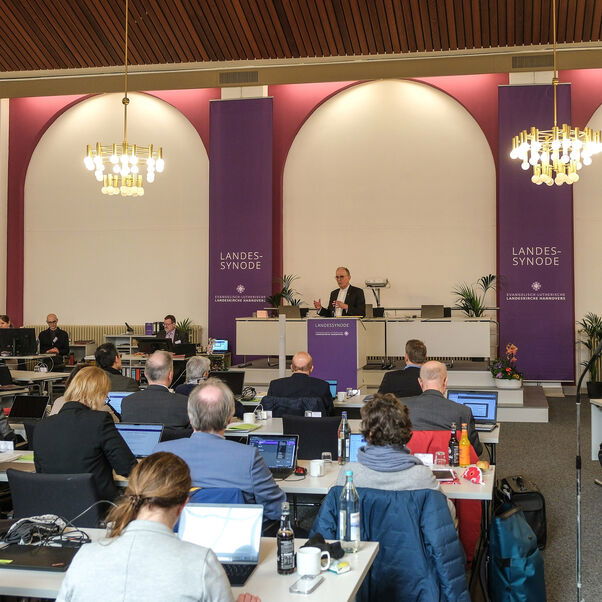 Mehrere Personen an Tischen in einem Sitzungssaal