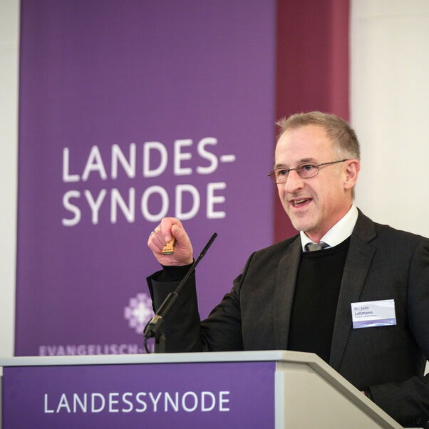 Eine männlich lesbare Person an einem Rednerpult