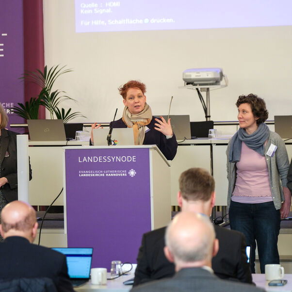 Mehrere Personen stehen um ein Rednerpult