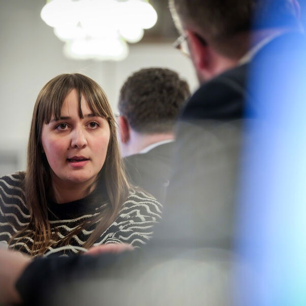 Eine weiblich lesbare Person unterhält sich mit einer anderen Person