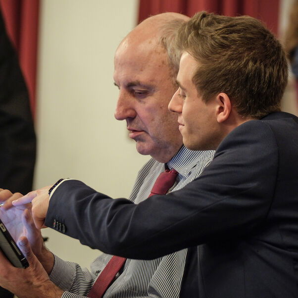 Zwei männlich lesbare Personen vor einem Bildschirm