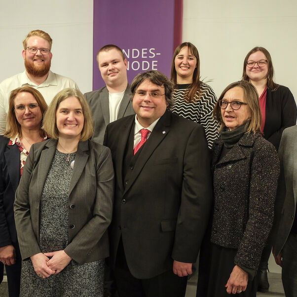 Sechs weiblich und vier männlich zu lesende Personen stehen als Gruppe zusammen und schauen in die Kamera.