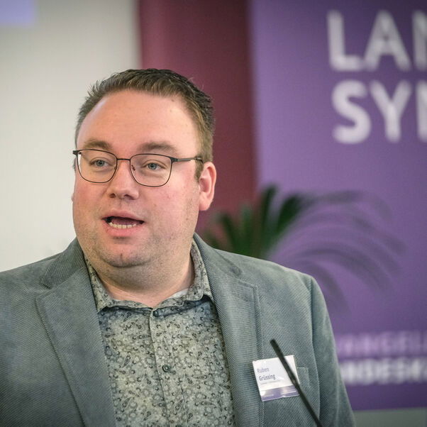 Eine männlich lesbare Person an einem Rednerpult