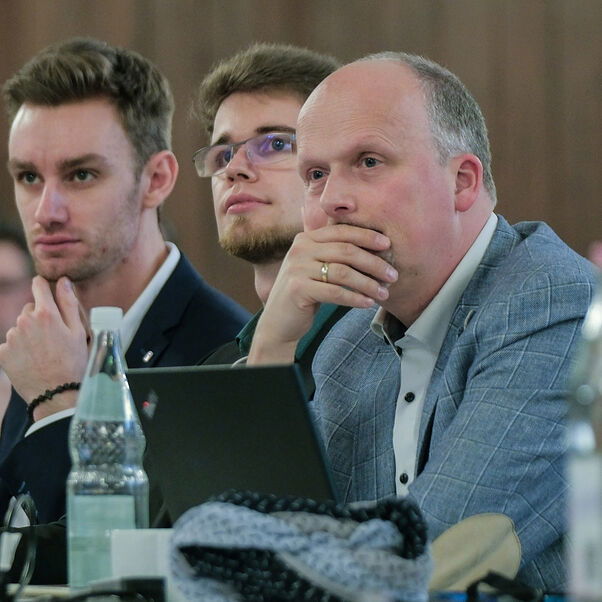 Mehrere Personen sitzen in einer Tischreihe