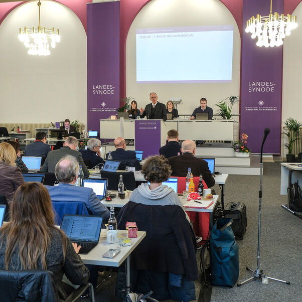 Viele Personen an Tischen in einem Sitzungssaal