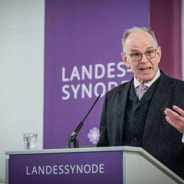 Eine männlich lesbare Person an einem Rednerpult