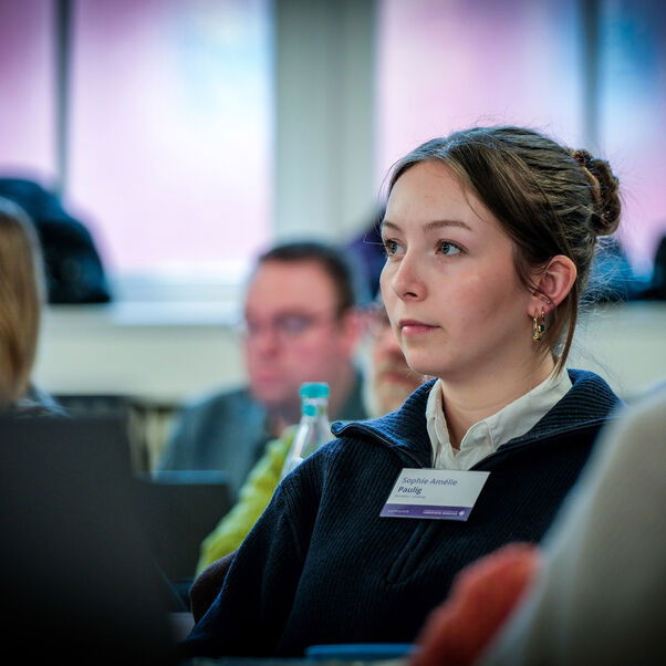 Eine weiblich lesbare Person in einer Tischreihe