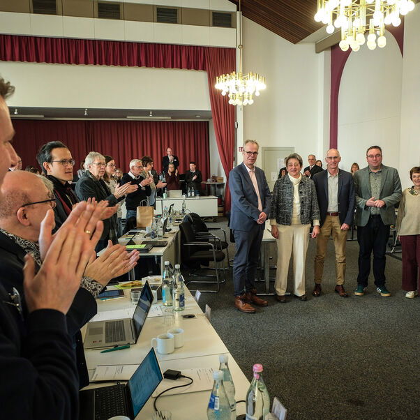 Mehrere Personen applaudieren in einem Sitzungssaal