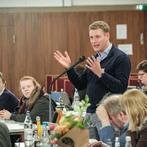 Eine männlich lesbare Person an einem Mikrofon