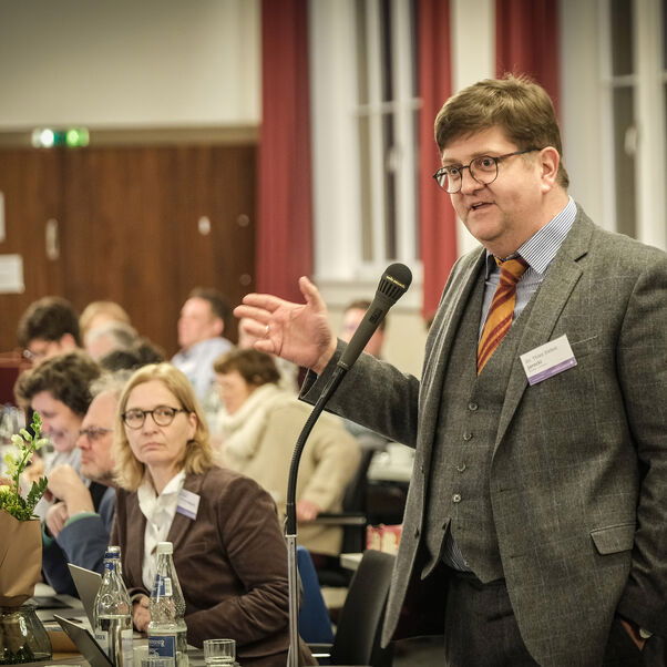 Eine männlich lesbare Person an einem Mikrofon