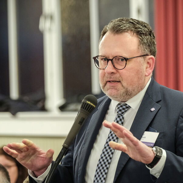 Eine männlich lesbare Person an einem Mikrofon