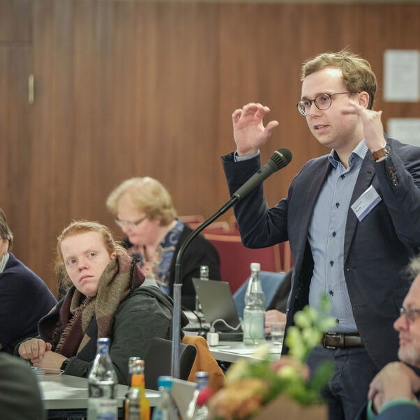 Eine männlich lesbare Person an einem Mikrofon