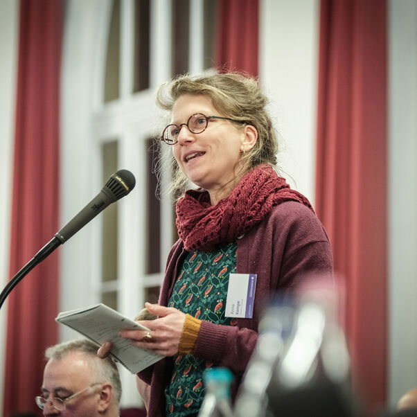 Eine weiblich lesbare Person an einem Mikrofon