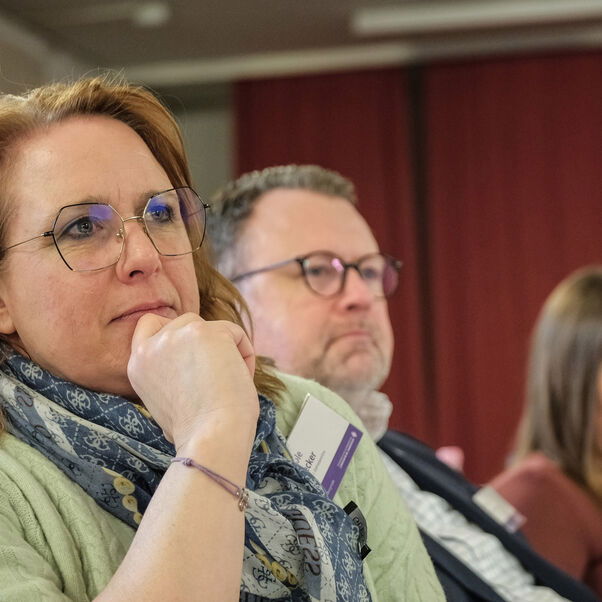 Mehrere Personen sitzen in einer Tischreihe