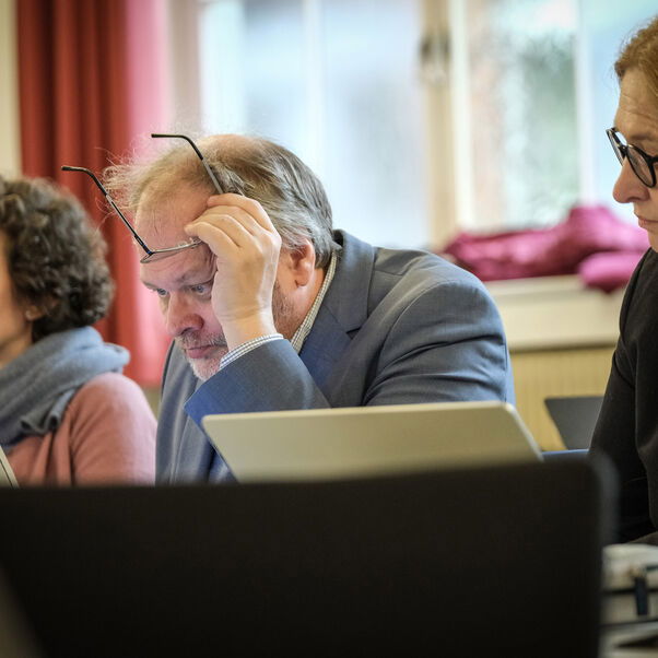 Mehrere Personen sitzen in einer Tischreihe