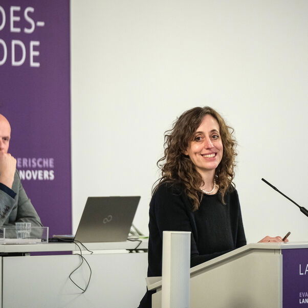 Eine weiblich lesbare Person an einem Rednerpult