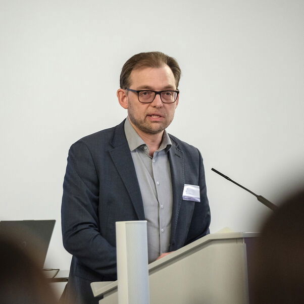 Eine männlich lesbare Person an einem Rednerpult